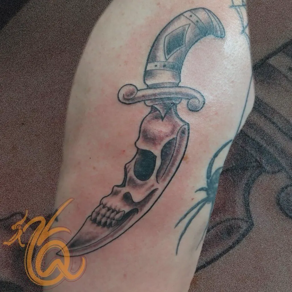 Black and grey dagger through a skull traditional tattoo